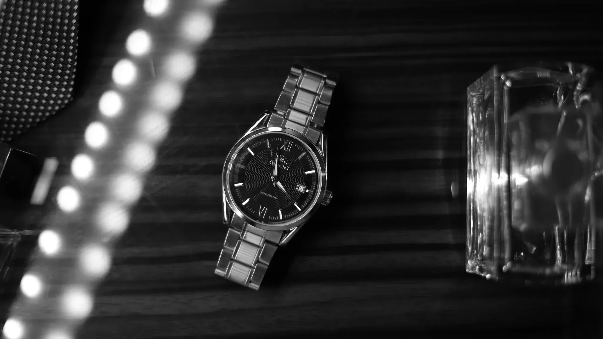 A stainless steel wristwatch with a dark dial resting on a wooden surface.